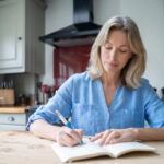 Woman at home writing on her journal