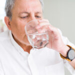 Handsome senior man drinking a fresh glass of water at home