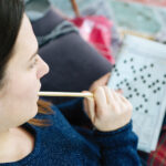 Female hand holding a pencil and solves crossword puzzle