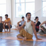 Male yoga instructor teaching class of five adults