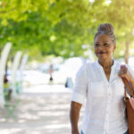 Female senior tourist smiles as she walks through city park