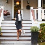 Businesswoman With Cup Of Coffee Leaving Suburban House For Work