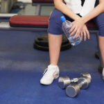 Low section of a tired and thoughtful woman in gym