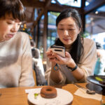 Woman taking picutre of dessert at cafe