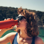 Young woman drinking water from an insulated bottle in nature