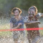 Two girls competing in a mud run for charity