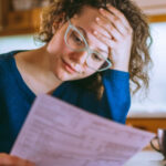 Woman in glasses revieiwing insurance info sheet