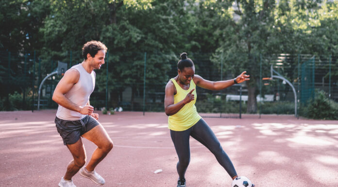 young sportsman and woman playing soccer on hardcourt