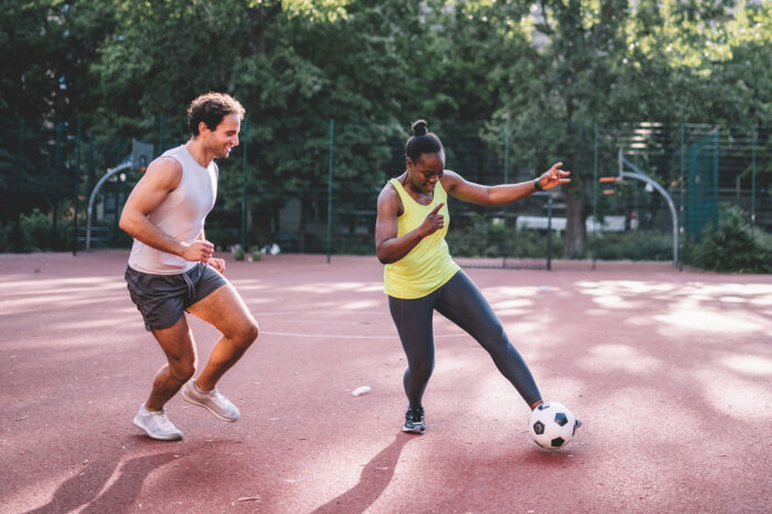 young sportsman and woman playing soccer on hardcourt