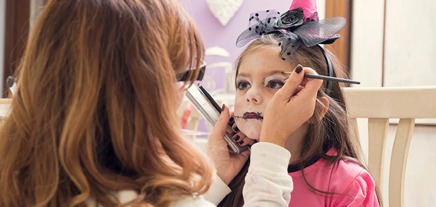 Mother applying make-up on daughter for Halloween