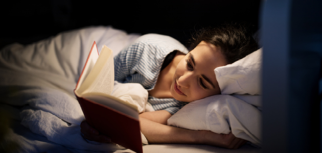 Femme lisant un livre dans un lit.