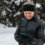 Femme heureuse à l’extérieur regardant son téléphone.