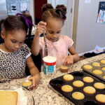 Two girls baking cupcakes in a kitchen