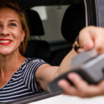 Femme souriant à la fenêtre d’un service au volant.