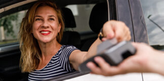 Femme souriant à la fenêtre d’un service au volant.