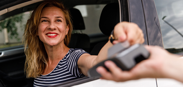 Femme souriant à la fenêtre d’un service au volant.