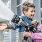 Deux enfants jouant avec un boyau d’arrosage.