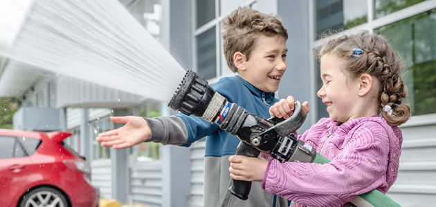 2 children spraying water with a hose