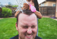 Fille faisant éclater un ballon d'eau sur la tête de son père