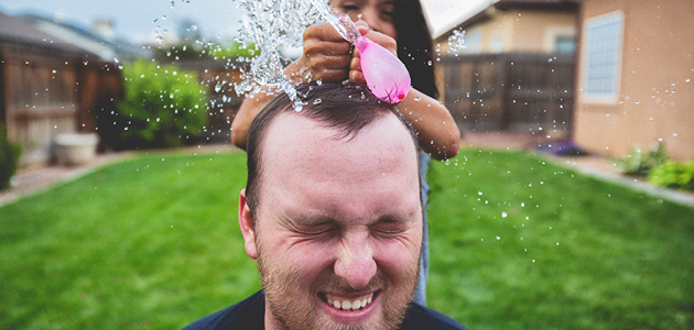 Girl popping water balloon on father’s head