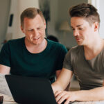 Two men sitting at a computer planning together