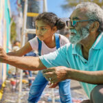 Older man and young girl painting a mural outside