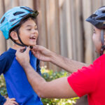 Man fastening helmet on child’s head