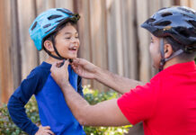 Man fastening helmet on child’s head