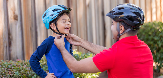 Man fastening helmet on child’s head