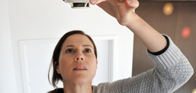 Woman changing smoke detector