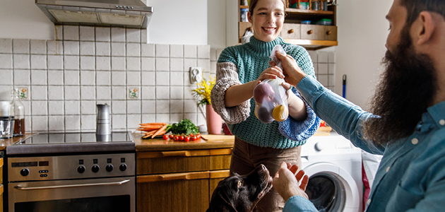 Man passing woman a bag of produce in the kitchen