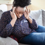 Woman sitting down holding her head in pain