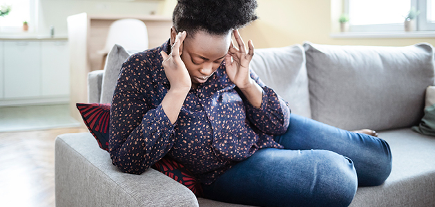 Woman sitting down holding her head in pain