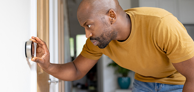 Homme vérifiant le thermostat de sa maison