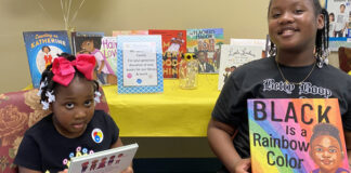 Young girls displaying books that celebrate Black History Month