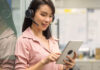 A woman wearing headphones and looking at a tablet