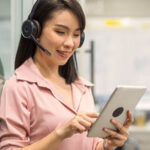 A woman wearing headphones and looking at a tablet