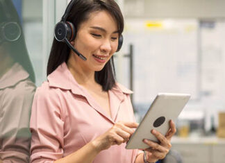 A woman wearing headphones and looking at a tablet